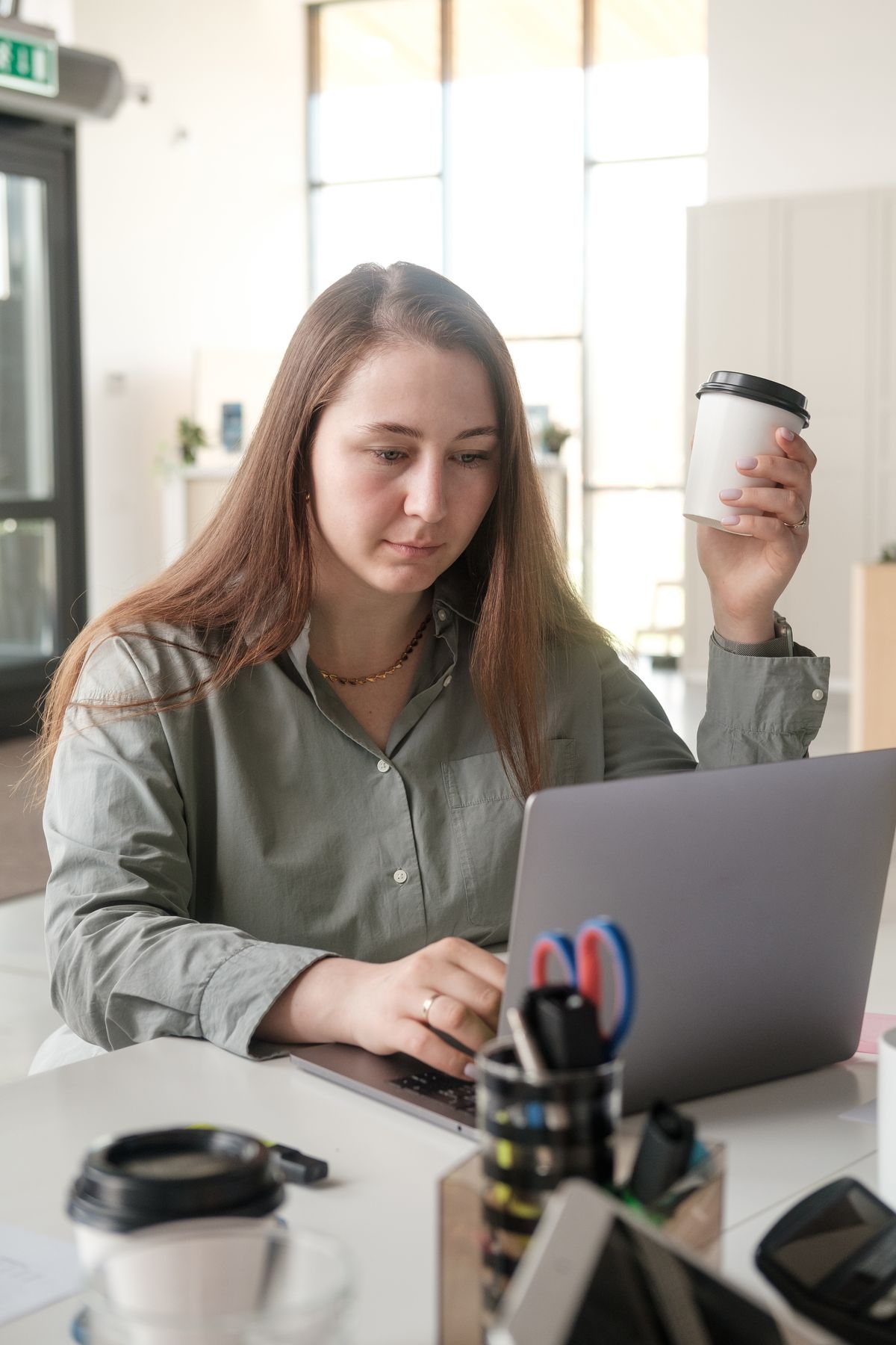 Une courtière commence sa journée devant son portable, café à la main