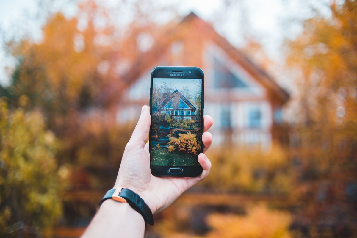 Une main photographie une maison avec un téléphone